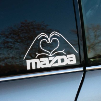 Štýlová nálepka na zadnom okne automobilu značky Mazda zobrazuje ruky formujúce tvar srdca. Tento biely, moderný dizajn vyniká na tmavom pozadí skla, čím dodáva vozidlu jedinečný a osobný dotyk. Perfektný doplnok pre majiteľov áut Mazda, ktorí chcú vyjadriť svoju lásku k tejto značke a zároveň hľadajú kreatívne a estetické dekorácie na svoje vozidlo. Ideálna voľba pre milovníkov áut, ktorí túžia ozdobiť svoje auto štýlovým a jedinečným prvkom.