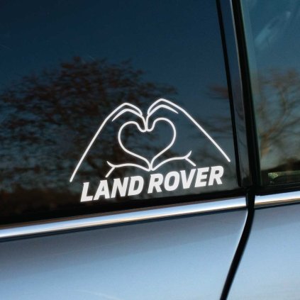 Na obrázku je originálna nálepka na bočnom okne vozidla Land Rover, zobrazujúca dve ruky formujúce srdce nad nápisom "LAND ROVER". Tento jedinečný a kreatívny dizajn je ideálny pre všetkých majiteľov Land Rover, ktorí chcú pridať svojmu autu osobitý dotyk. Nálepka symbolizuje vášeň a lásku k značke, čím sa váš Land Rover odlíši od ostatných vozidiel na cestách. Elegantný dizajn dodáva vozidlu jedinečný štýl a vizuálne zaujme každého okoloidúceho. Perfektný spôsob, ako prejaviť svoju oddanosť tejto prestížnej značke.