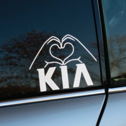 Na fotografii je nálepka na bočnom okne auta, ktorá zobrazuje obrys rúk formujúcich srdce nad nápisom "KIA". Umiestnená na tmavom skle, vytvára kontrastný a výrazný efekt. Táto štýlová nálepka je ideálna pre všetkých fanúšikov značky KIA, ktorí chcú svojmu vozidlu dodať osobitý a emotívny dotyk. Perfektný doplnok na zvýraznenie vášho auta a vyjadrenie lásky k tejto obľúbenej automobilovej značke.