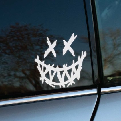 Plotrovaná nálepka na auto s grimasujúcou tvárou, prekríženými očami a výrazným zubatým úsmevom v graffiti štýle.