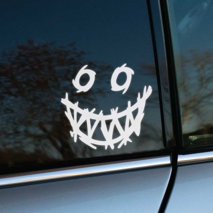 Plotrovaná nálepka na auto s kreslenou tvárou so špirálovitými očami a šialeným úsmevom s ostrými zubami.