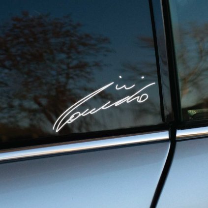 Plotrovaná nálepka s autentickým podpisom Nikiho Laudu v elegantnom písanom štýle s plynulými líniami a dynamickým charakterom písma.