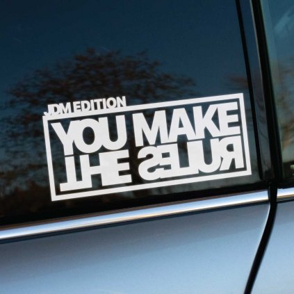 Biela samolepka s textom „JDM Edition - YOU MAKE THE RULES“ v štýlovom dizajne s obráteným nápisom „THE RULES“ je výrazným doplnkom pre milovníkov JDM a tuningovej kultúry. Tento dizajn vyjadruje nezávislosť a odvahu ísť vlastnou cestou, čo je charakteristické pre tuningových nadšencov, ktorí svoje autá upravujú podľa vlastných pravidiel. Samolepka vynikne na tmavom okne auta a dodáva mu unikátny, rebelantský štýl, ktorý zdôrazňuje osobnosť a sebavedomie majiteľa.