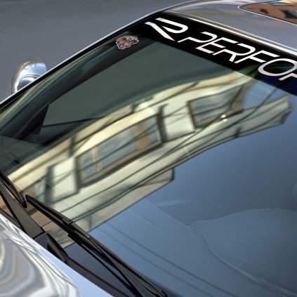 Sunstrip s veľkým bielym nápisom R PERFORMANCE v detaile na čelnom skle BMW. Text vypĺňa väčšinu čiernej plochy.