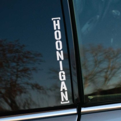 Plotrovaná nálepka s vertikálnym nápisom v hranatých zátvorkách, ktorý obsahuje text v presnom znení [HOONIGAN].