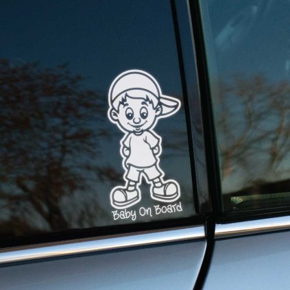 Plotrovaná nálepka, usmiata kreslená postavička chlapca v šiltovke a v krátkych nohaviciach s nápisom Baby On Board dole.