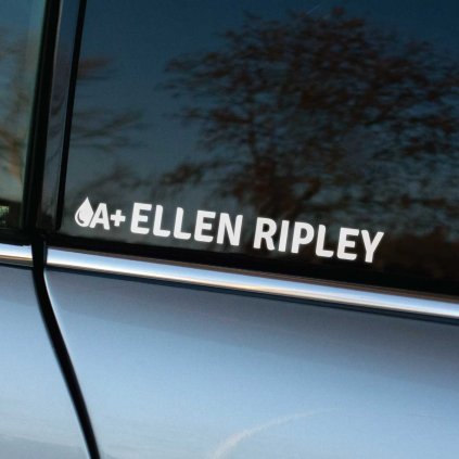 Plotrovaná nálepka na auto s menom „Ellen Ripley“ a symbolom kvapky krvi s krvným typom A+ v čistom typografickom dizajne.