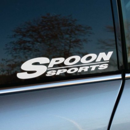 Na fotke je detail zadného okna auta s bielou nálepkou „Spoon Sports“ v jednoduchom, no výraznom písme. Táto nálepka odkazuje na známu japonskú spoločnosť špecializujúcu sa na tuning a vysokovýkonné diely pre športové automobily, najmä značky Honda. Biela nálepka kontrastuje s tmavým sklom auta, čím pridáva športový a dynamický vzhľad. Ideálna pre fanúšikov pretekárskej kultúry a motoristického tuningu, ktorí chcú zdôrazniť svoju vášeň pre výkon a rýchlosť.