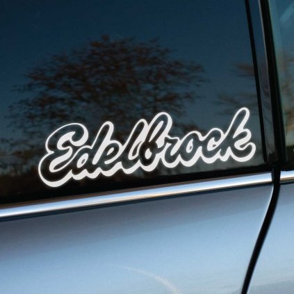 Biela nálepka "Edelbrock" s elegantným písaným písmom na zadnom bočnom okne strieborno-sivého auta. Dizajn nálepky pôsobí štýlovo a zároveň športovo, pričom vyniká na tmavom tónovanom skle vozidla. Ideálna voľba pre milovníkov automobilového tuningu a značiek spojených s výkonnými motormi.  **Kľúčové slová:** nálepka na auto, samolepka Edelbrock, automobilová nálepka, tuningová nálepka, logo Edelbrock, nálepka na sklo auta, auto dekorácia, personalizácia auta, športové nálepky, doplnky na auto.