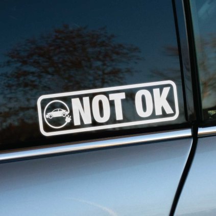 Plotrovaná nálepka „NOT OK“ s ikonou auta pripojeného na elektrickú zástrčku. Vyjadruje nesúhlas s elektrickými vozidlami.