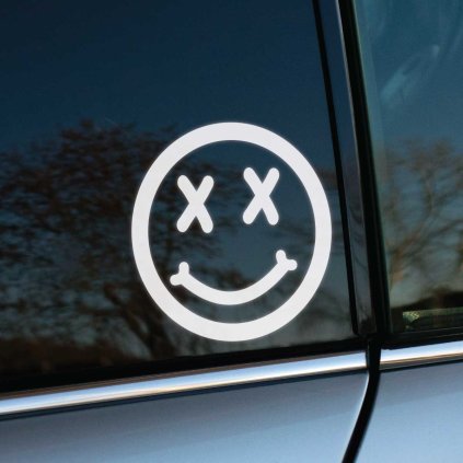 Plotrovaná nálepka na auto s úsmevnou tvárou, preškrtnutými očami a úsmevom zakončeným kosťami v štýle Nirvana.