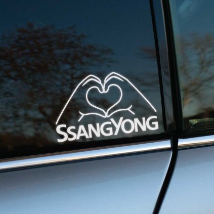 Plotrovaná nálepka s textom „SSANGYONG“ a siluetou rúk tvoriacich srdce. Perfektný spôsob, ako vyjadriť vášeň pre túto kórejskú značku.