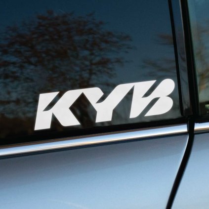 Plotrovaná nálepka s logom KYB v hrubom šikmom písme s ostrými hranami a zaoblenými koncami.