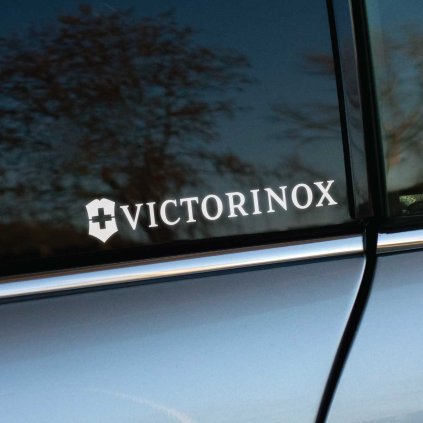 Plotrovaná nálepka na auto s logom Victorinox, štít so švajčiarskym krížom vedľa elegantného nápisu v klasickom písme.