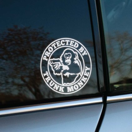 Plotrovaná nálepka na auto s motívom opice s pištoľou a textom „Protected by Trunk Monkey“ v kruhovom dynamickom dizajne.