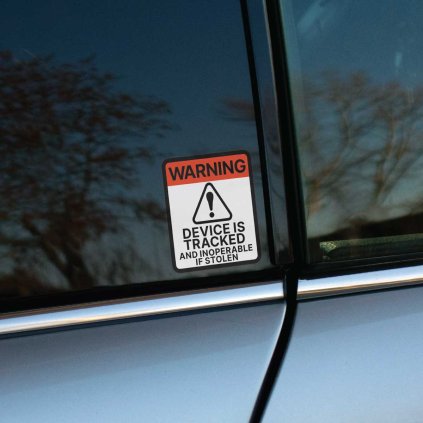 Tlačená nálepka s výstražným symbolom a textom „Device is tracked and inoperable if stolen“, vhodná proti krádeži.
