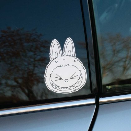 Plotrovaná nálepka na auto s motívom Labubu hlavy so zavretými očami a širokým veselým zubatým úsmevom.