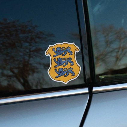 Tlačená nálepka na auto s estónskym štátnym erbom – tri modrí levy v žltom štíte s bielym okrajom.