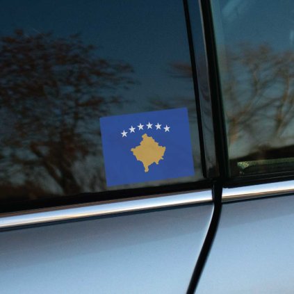 Tlačená nálepka s vlajkou Kosova, modré pole so zlatou siluetou krajiny a šiestimi bielymi hviezdami v oblúku nad ňou.