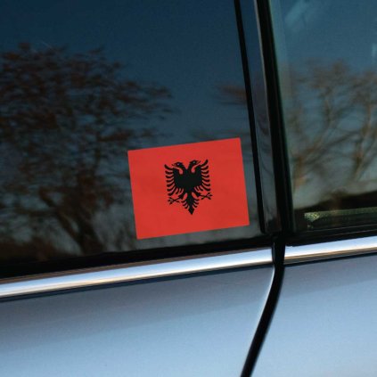 Tlačená nálepka s vlajkou Albánska, červené pole s čiernym dvojhlavým orlom rozprestierajúcim krídla a zdobeným detailným perím.