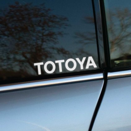 Plotrovaná nálepka s nápisom TOTOYA vo veľkých tlačených písmenách, určená pre vtipnú alebo parodickú úpravu názvu značky.