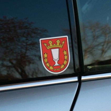 Tlačená nálepka na auto s erbom obce Lednické Rovne, zobrazuje strieborný pohár s korunou a zlatým vencom na červenom štíte.