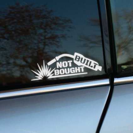 Plotrovaná nálepka s motívom zváracieho horáka s iskrami a nápisom v troch riadkoch v presnom znení: BUILT NOT BOUGHT.