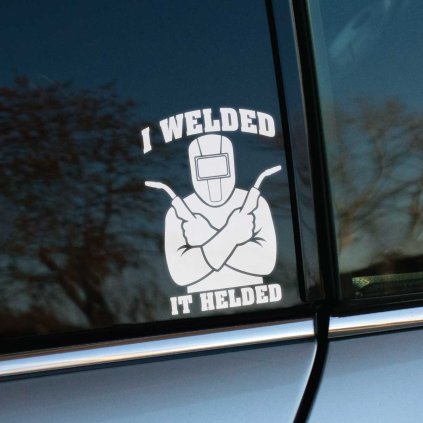 Plotrovaná nálepka s postavou zvárača držiaceho horáky a textom „I welded it helded“, vtipný motív pre fanúšikov zvárania.