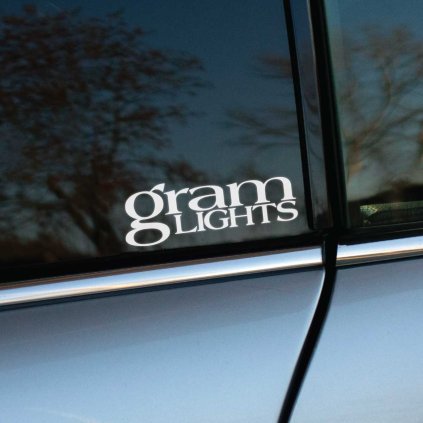 Plotrovaná nálepka s textovým logom "gram LIGHtS" s presahujúcim dizajnom písmen, obľúbená značka v tuning komunite.