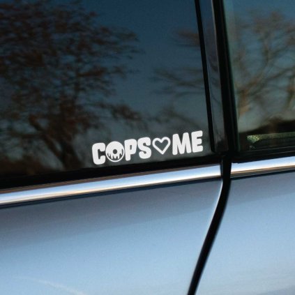 Plotrovaná nálepka na auto s textom „COPS♥️ME“. Písmeno O je nahradené kresleným donutom a symbol srdca je namiesto slova "love".