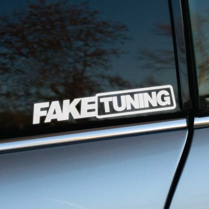 Plotrovaná nálepka s textom FAKE TUNING v modernom hrubom písme, kde je druhé slovo vizuálne ohraničené v obdĺžnikovom ráme.