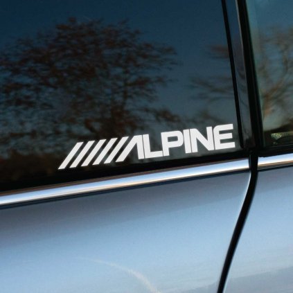 Biela nálepka „ALPINE“ s dynamickým dizajnom štyroch šikmých čiar je nalepená na bočnom okne sivého automobilu. Táto moderná nálepka zdôrazňuje prepojenie so značkou Alpine, známou svojimi špičkovými audio a multimediálnymi systémami pre autá. Minimalistický a štýlový dizajn robí z tejto nálepky perfektný doplnok pre každého motoristického nadšenca, ktorý chce dodať svojmu vozidlu elegantný a technicky vyspelý vzhľad. Ideálna pre fanúšikov personalizácie a kvalitných doplnkov na auto.