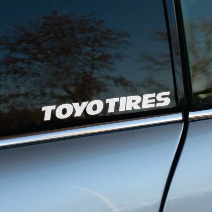 Nálepka „Toyo Tires“ nalepená na zadnom bočnom okne auta. Jednoduchý, no výrazný dizajn s moderným písmom zvýrazňuje športový a profesionálny charakter vozidla. Lesklé sklo s odrazom prírody dodáva nálepke vizuálnu hĺbku a precíznosť. Ideálna pre fanúšikov kvalitných pneumatík a automobilových doplnkov, ktorí chcú dodať svojmu autu štýlový detail.