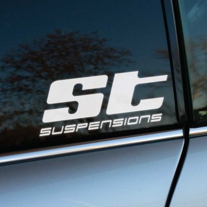 Nálepka s logom „ST suspensions“ nalepená na zadnom bočnom okne auta. Športový a moderný dizajn zvýrazňuje dynamiku a výkon, pričom čisté línie písma dodávajú vozidlu profesionálny vzhľad. Lesklý povrch skla s odrazom stromov dotvára estetickú harmóniu a podčiarkuje kvalitu prevedenia nálepky. Perfektná voľba pre automobilových nadšencov a fanúšikov úprav podvozku.