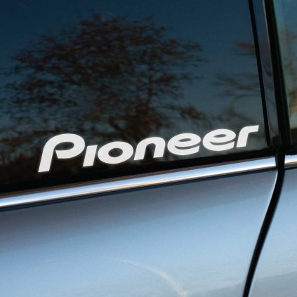 Biela nálepka „Pioneer“ na bočnom okne auta vyniká svojím jednoduchým a elegantným dizajnom. Tmavé sklo zvýrazňuje kontrast bieleho loga, čím nálepka pôsobí štýlovo a profesionálne. Strieborná karoséria auta dopĺňa moderný vzhľad nálepky, ktorá je ideálna pre fanúšikov audio techniky a motoristov, ktorí chcú svoje vozidlo personalizovať. Perfektný doplnok pre propagáciu značky alebo individuálny štýl. Kľúčové slová: nálepka Pioneer, nálepky na auto, dizajn na okno, štýlové doplnky pre auto.