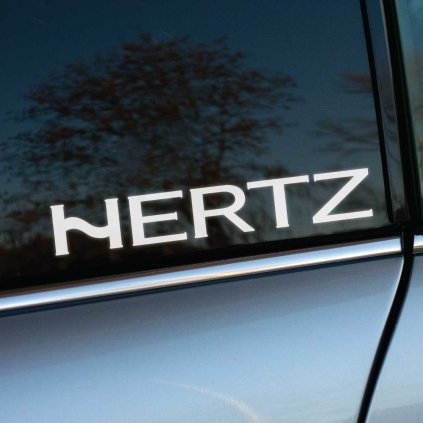 Biela nálepka „Hertz“ s moderným a elegantným dizajnom, nalepená na tmavom bočnom okne auta. Ikonické logo značky, známej svojou špecializáciou na špičkový audio systém, vyniká kontrastom na tmavom skle a dodáva vozidlu štýlový a profesionálny vzhľad. Strieborná karoséria auta umocňuje čistý a sofistikovaný dojem z tejto nálepky. Ideálna pre audio nadšencov a motoristov, ktorí chcú podporiť kvalitu a precíznosť značky Hertz. Kľúčové slová: nálepka Hertz, audio systém, tuning doplnky, nálepky na auto, štýlové doplnky, personalizácia vozidla.