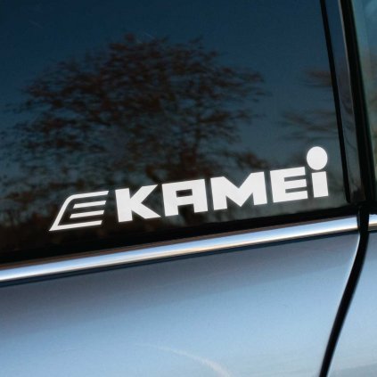 Biela nálepka „Kamei“ s dynamickým písmom a výrazným symbolom „E“ na začiatku je nalepená na tmavom bočnom okne auta. Tento dizajn stelesňuje moderný a športový štýl, pričom čisté línie loga sú zvýraznené kontrastom tmavého skla. Strieborná karoséria vozidla podčiarkuje elegantný vzhľad nálepky. Ideálna voľba pre motoristov a tuningových nadšencov, ktorí chcú propagovať kvalitu a inováciu značky Kamei, známej svojimi automobilovými doplnkami. Kľúčové slová: nálepka Kamei, tuningové doplnky, športový dizajn, nálepky na auto, personalizácia vozidla.