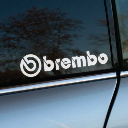 Biela nálepka „Brembo“ s ikonickým logom v podobe kruhového symbolu nalepená na tmavom bočnom okne auta. Tento dizajn zvýrazňuje precíznosť a vysoký výkon, ktorý značka Brembo symbolizuje v oblasti brzdových systémov. Kontrast bielej farby na tmavom skle a strieborná karoséria auta vytvárajú čistý a profesionálny vzhľad. Perfektné pre tuningových nadšencov a motoristov, ktorí chcú zdôrazniť svoj záväzok k kvalite a štýlu. Kľúčové slová: nálepka Brembo, tuningové doplnky, brzdové systémy, nálepky na auto, športový dizajn, personalizácia vozidla.