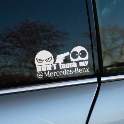 Plotrovaná nálepka s textom „Don’t touch my Mercedes“, zamračená tvár so zbraňou mieri na prekvapenú tvár.