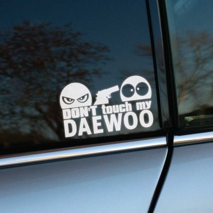 Vyrezávaná nálepka s textom „Don’t touch my Daewoo“, zamračená tvár drží pištoľ a mieri na udivenú tvár.