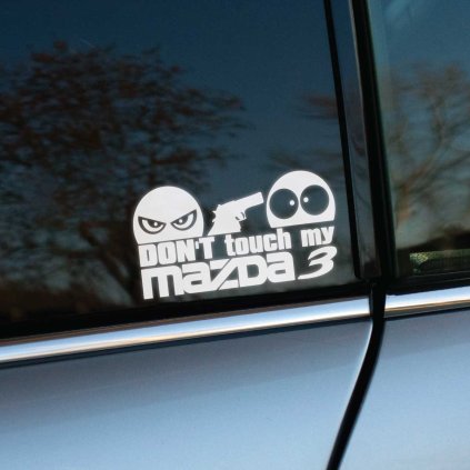 Vyrezávaná nálepka s nápisom „Don’t touch my Mazda 3“, nahnevaná tvár drží pištoľ a mieri na prekvapenú tvár.