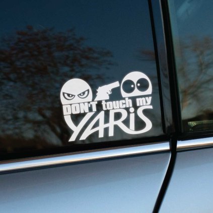 Plotrovaná nálepka s nápisom “Don’t touch my Yaris”, zamračená tvár mieri pištoľou na udivenú tvár.