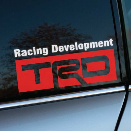 Výrazná nálepka „Racing Development TRD“ spája biely text s veľkým červeným logom „TRD“, umiestnená na tmavom bočnom okne strieborného auta. Jednoduché, ale výrazné spracovanie symbolizuje športovú DNA značky TRD (Toyota Racing Development) a jej zameranie na vysokovýkonné technológie. Jasná kombinácia červenej, bielej a čiernej farby vytvára atraktívny kontrast, ktorý okamžite upúta pozornosť a podčiarkuje dynamiku vozidla. Ideálny autodoplnok pre tuning nadšencov, ktorí chcú vyjadriť vášeň pre pretekárske technológie a prémiový dizajn.  Kľúčové slová: nálepka TRD, Racing Development, tuning auta, športové doplnky, nálepky na auto, personalizácia vozidla, závodný štýl.