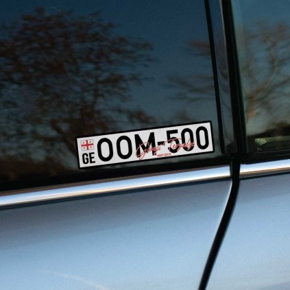 Tlačená nálepka na auto v štýle gruzínskej ŠPZ s nápisom OOM-500, podpisom Giorgi Revazishvili a rokmi 1987–2013.