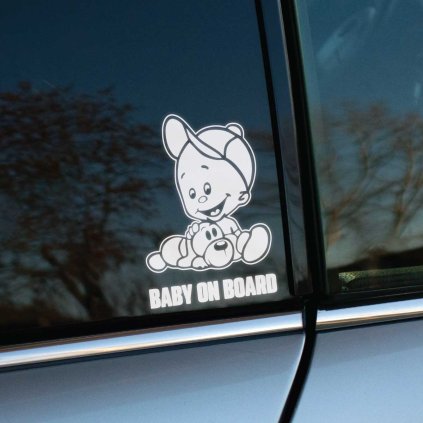 Plotrovaná nálepka na auto s motívom usmievavého chlapca v šiltovke, sediaceho pri plyšovom psíkovi a textom BABY ON BOARD.