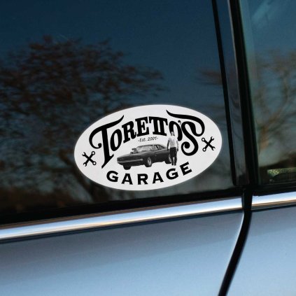 Tlačená nálepka na auto v oválnom tvare s nápisom Toretto’s Garage, siluetou auta a postavou inšpirovanou Fast & Furious.