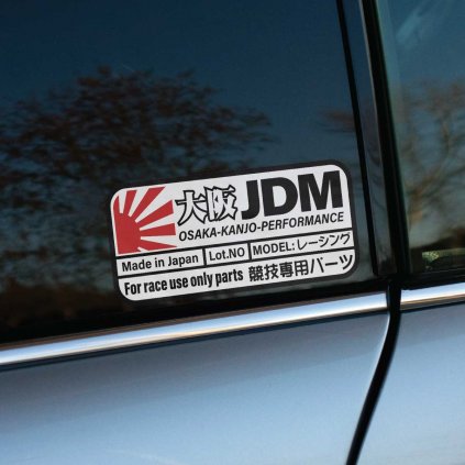 Táto samolepka „Osaka JDM - Kanjo Performance“ so štýlovým dizajnom inšpirovaným japonským automobilovým priemyslom je ideálnym doplnkom pre každého nadšenca JDM a kanjo scény. Dizajn s červeným symbolom vychádzajúceho slnka a nápismi ako „Made in Japan“ a „For race use only parts“ odkazuje na kvalitné diely a tuningové prvky určené pre pouličné preteky, ktoré sú populárne na osackom okruhu Kanjo. Táto samolepka vyniká na tmavom okne auta a dodáva mu autentický vzhľad, ktorý ocení každý fanúšik japonskej tuningovej kultúry a závodného štýlu.