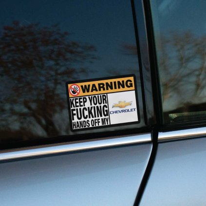 Varovná tlačená nálepka obdĺžnikového tvaru s textom: „KEEP YOUR FUCKING HANDS OFF MY CHEVROLET“ a výrazným preškrtnutým symbolom ruky.