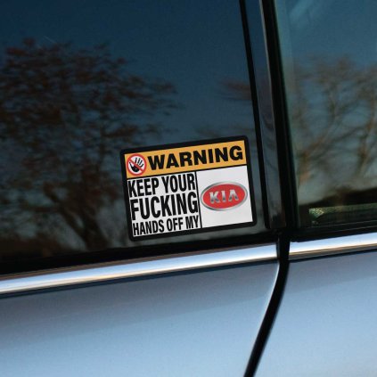 Tlačená nálepka obdĺžnikového tvaru s varovaním: „KEEP YOUR FUCKING HANDS OFF MY KIA“, doplnená o preškrtnutý symbol ruky.