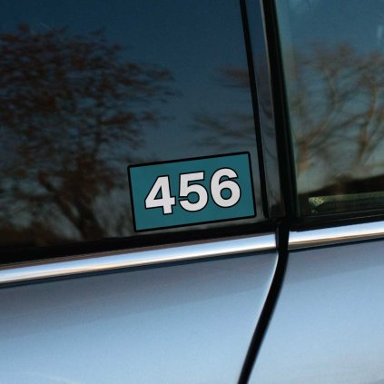 Tlačená nálepka na auto s číslom 456 v štýle seriálu Squid Game, výrazný dizajn na modrom pozadí s čiernym rámom.